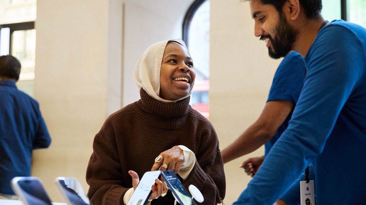 Cliente prenant en main un iPhone 15 lors d’un échange avec un conseiller